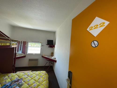 a room with a yellow door and a bed and a desk at HOTEL PARIS VALENCE in Bourg-de-Péage
