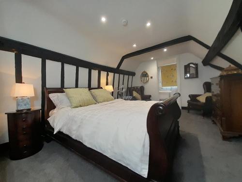 a bedroom with a large wooden bed with white sheets at Stone Court House in Maidstone