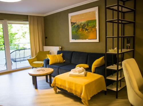 uma sala de estar com um sofá azul e almofadas amarelas em Nadmorskie Tarasy Apartament Park i Morze em Kolobrzeg