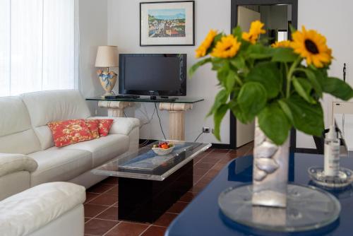 a living room with a white couch and a vase with sunflowers at Magnificent Villa Sanremo in Sanremo