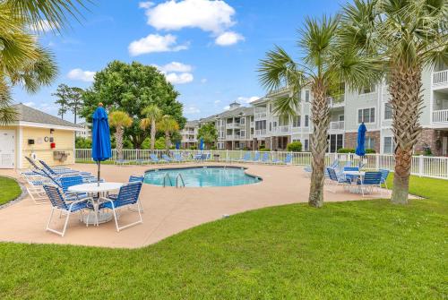 a pool with chairs and a table with umbrellas at Stunning 3BR Condo near Myrtlewood Golf Resort and Beach in Myrtle Beach