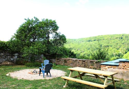 a picnic table and two chairs next to a stone wall at LE CLOS DES PIERRES ROUGES in Burgy