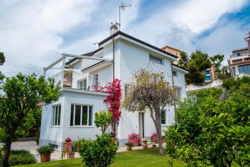a white house with a balcony and flowers at Magnificent Villa Sanremo in Sanremo
