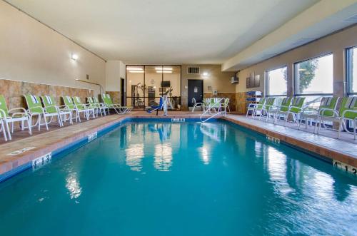 a swimming pool with chairs and blue water in a house at Comfort Inn & Suites Near Worlds of Fun in Kansas City