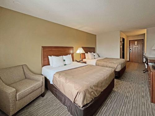 a hotel room with two beds and a chair at Quality Inn Mitchell I-90 in Mitchell