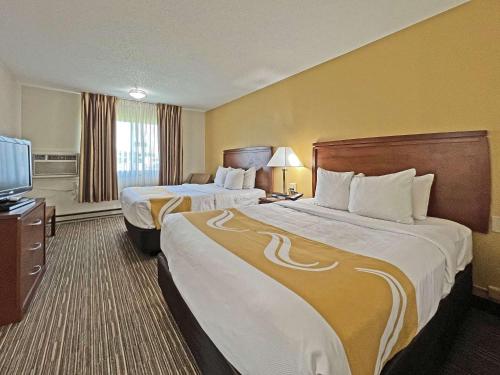 a hotel room with two beds and a flat screen tv at Quality Inn Mitchell I-90 in Mitchell