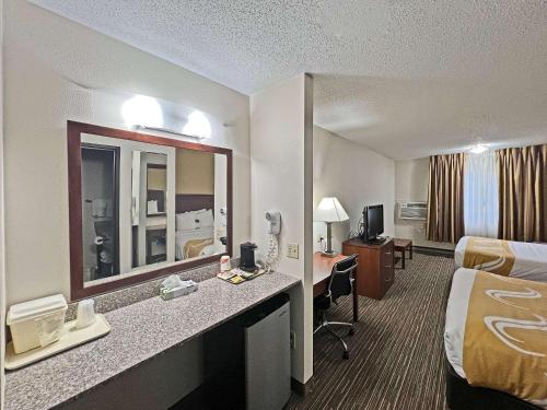 a hotel room with a bed and a desk with a mirror at Quality Inn Mitchell I-90 in Mitchell