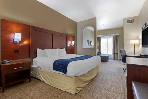 a hotel room with a large bed and a desk at Comfort Suites Gainesville in Gainesville