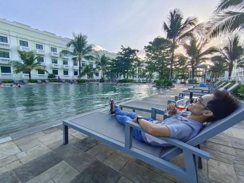 a woman laying on a bench next to a pool at Minh Anh Hotel in Phu Quoc