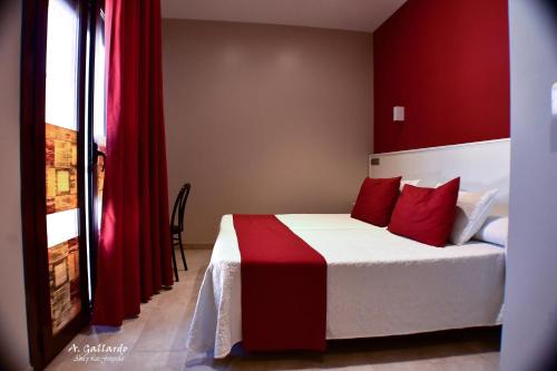 a bedroom with a red and white bed with red pillows at Hostal Playa Candor in Rota