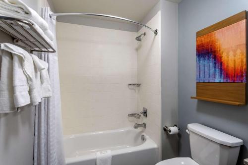 a bathroom with a white tub and a toilet at MainStay Suites in Bowling Green
