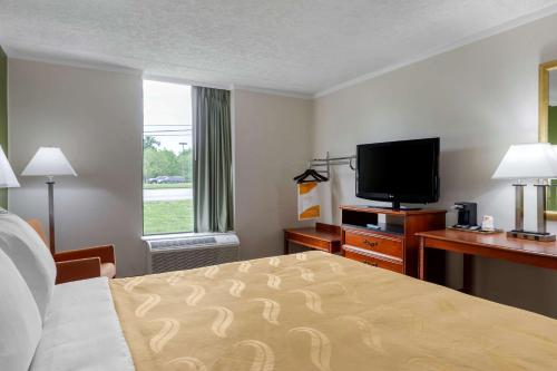 a hotel room with a bed and a flat screen tv at Quality Inn - Roxboro South in Roxboro