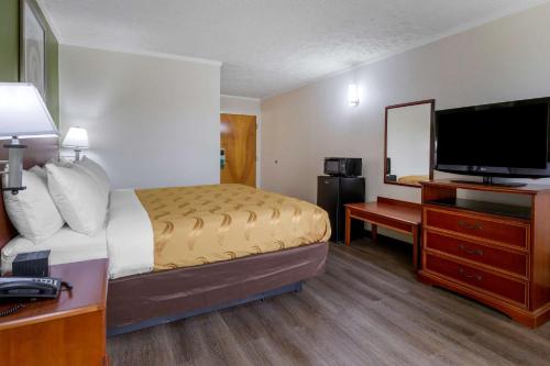 a hotel room with a bed and a flat screen tv at Quality Inn - Roxboro South in Roxboro