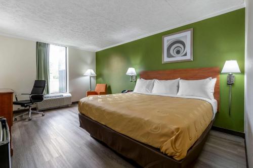 a hotel room with a bed and a green wall at Quality Inn - Roxboro South in Roxboro