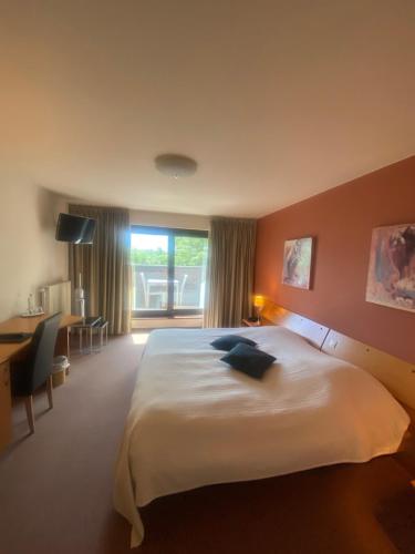 Schlafzimmer mit einem großen weißen Bett und einem Schreibtisch in der Unterkunft Hotel Gowell Kuur- en Wellness Yolande Buekers in Wellen