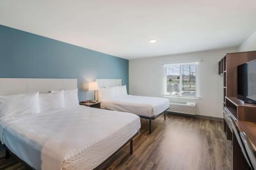 a hotel room with two beds and a flat screen tv at WoodSpring Suites Round Rock-Austin North in Round Rock