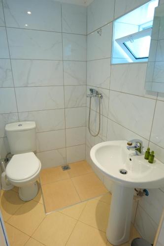 La salle de bains blanche est pourvue de toilettes et d'un lavabo. dans l'établissement Saranda Landscape, à Nivicë