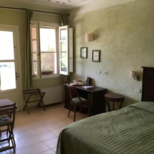 a hotel room with a bed and a desk and windows at Il Melograno Country House in Saturnia