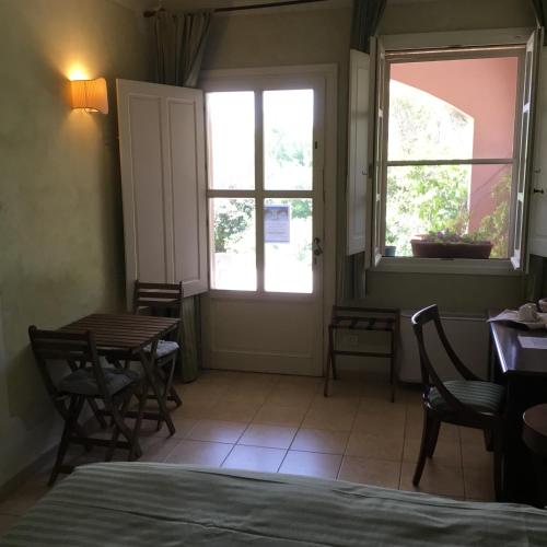 a room with a bed and a table and windows at Il Melograno Country House in Saturnia