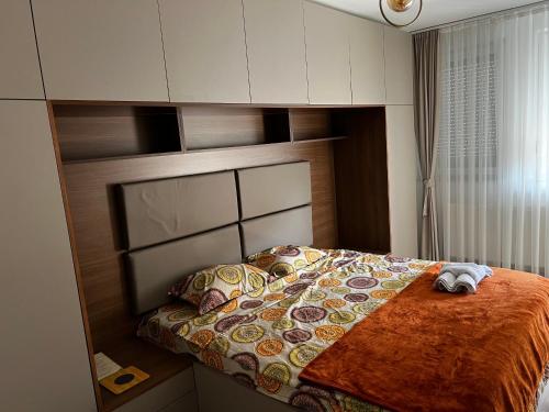 a small bedroom with a bed with a large headboard at Elegant Apartment in City Centre in Pristina