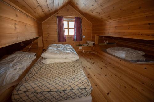 two beds in a log cabin with a window at Myraleited 40 in Tjørhom