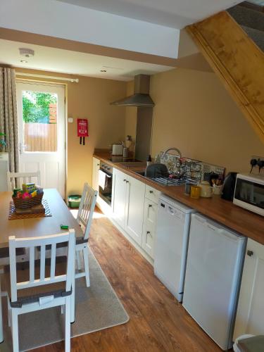 a kitchen with white appliances and a table and chairs at Riverwood Retreat - Self Contained Lux Apartment, Close to the Celtic Resort in Kemeys Inferior