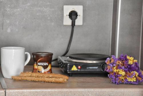 a counter with a toaster and a cup and flowers at Anemomylos Apartments in Lixouri