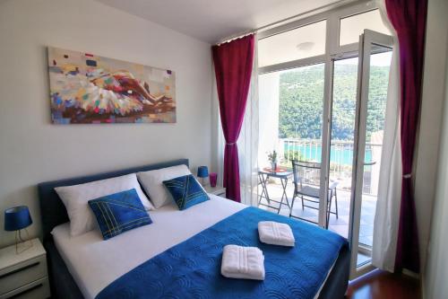 a bedroom with a blue and white bed and a balcony at Bonki apartment private free parking in Mokošica