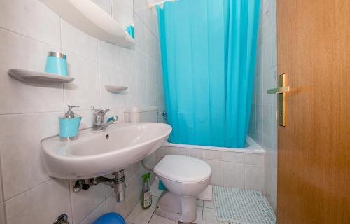 a bathroom with a sink and a toilet and a blue shower curtain at B&B Sabina Rooms & Apartments in Rab