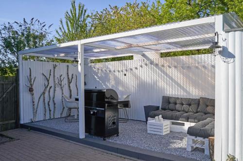 Una pérgola blanca con un sofá y una mesa. en Reetdachhaus De Ole Kaat, en Niesgrau
