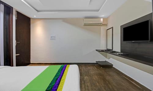 a bedroom with a bed and a tv on the wall at Treebo JJ Residency in Bengaluru