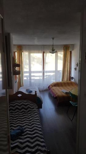 een slaapkamer met 2 bedden en een groot raam bij Studio 4 couchages vue pistes in Gréolières les Neiges