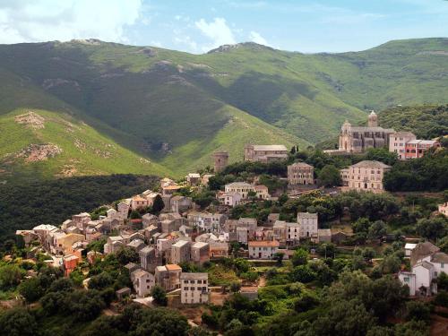 eine Stadt auf einem Hügel mit Bergen im Hintergrund in der Unterkunft Rogliano Maison de charme avec vue panoramique in Rogliano