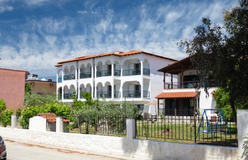 a white house with a fence in front of it at Studios Halkia in Toroni