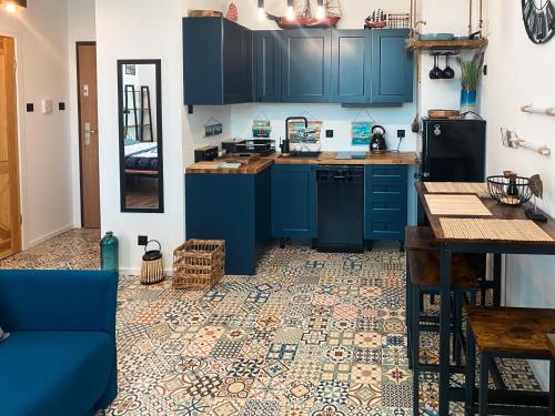 a kitchen with blue cabinets and a tile floor at Apartament TURKUS in Puck