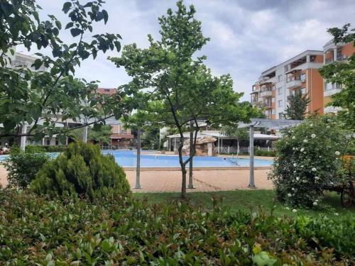 a swimming pool at a resort with trees and bushes at Apartment in Sunny beach, Complex Sun Village, 80 qm, 2 bedrooms & living room near to the beach, SWIMMING POOL, garden in Sunny Beach