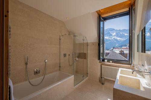 a bathroom with a tub and a shower and a sink at Hôtel National Resort & Spa in Champéry