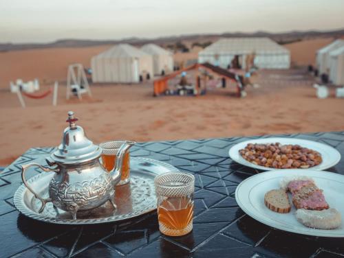 a table with a tea kettle and plates of food at Camel Luxury Camp in Merzouga