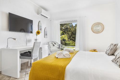a white bedroom with a bed and a desk and a window at Vista Portuguesa by OCvillas in Albufeira