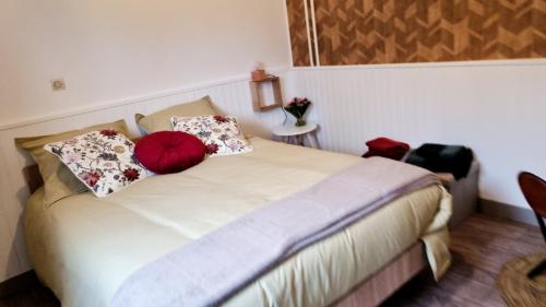 a bedroom with a bed with a red pillow on it at Hôtel restaurant du Commerce in Poulainville