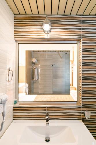 a bathroom with a sink and a large mirror at Ekaterini Hotel in Kiotari