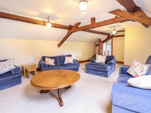 una sala de estar con sofás azules y una mesa de madera. en The Coach House en Llanymynech