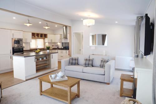 a white living room with a couch and a table at Trefalun Park in Tenby