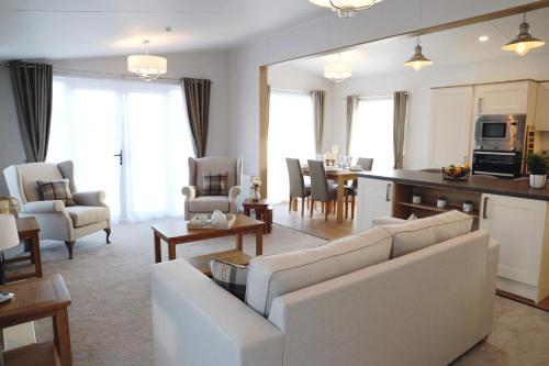 a living room with a white couch and a kitchen at Trefalun Park in Tenby