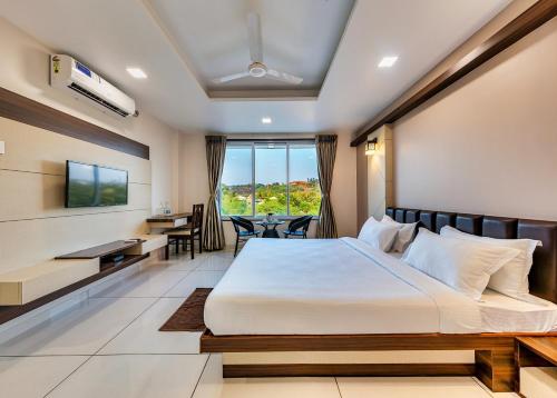 een hotelkamer met een groot bed en een bureau bij Hotel Grand Indu, 3 Star Kolhapur in Kolhapur