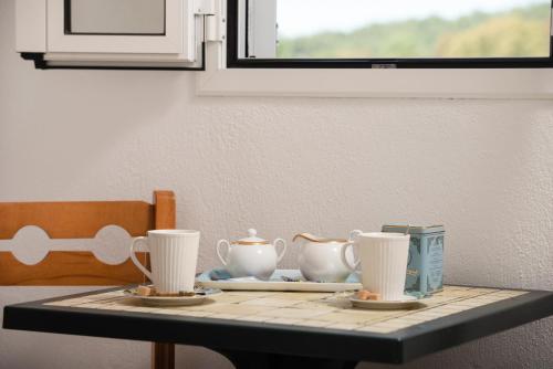 a table with three tea cups and a plate on it at Studios Halkia in Toroni