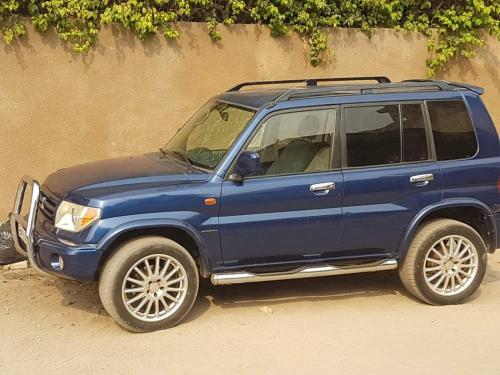 a blue jeep parked on a dirt road at Superbe appartement en résidence in Cotonou