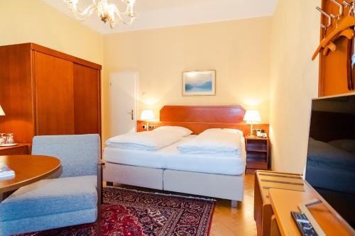 a bedroom with a bed and a desk and a television at Pension Elfy in Baden