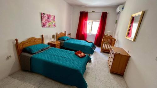 2 camas en una habitación pequeña con cortinas rojas en Sea view and valley view flat in Marsalforn, en Marsalforn