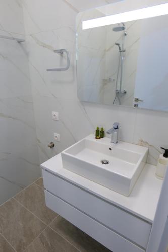 a white bathroom with a sink and a mirror at Saranda Landscape in Sarandë